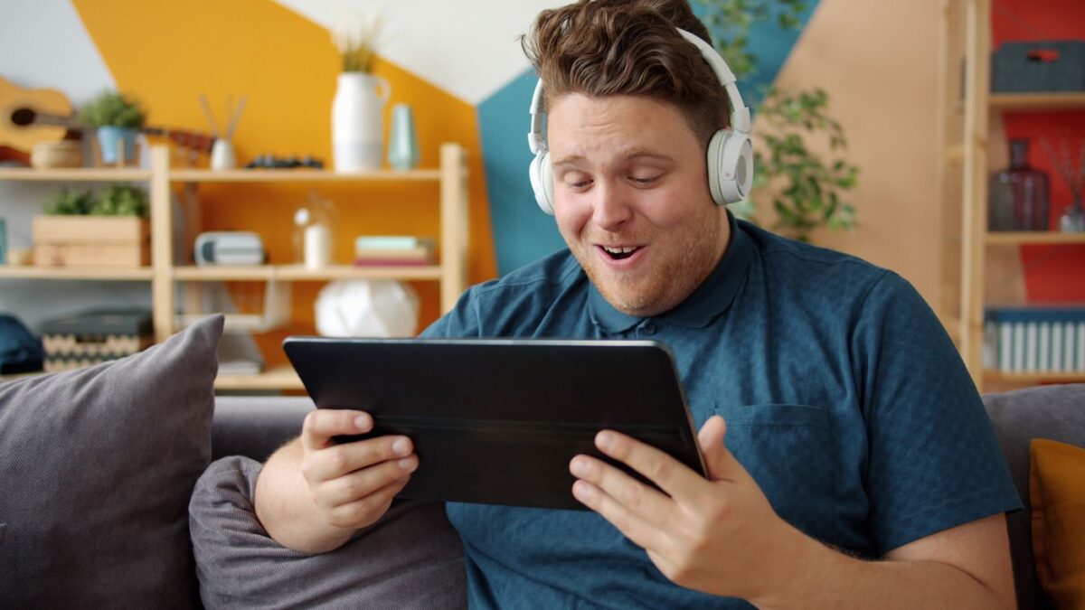 Kulaklıkla tablet kullanan kişi