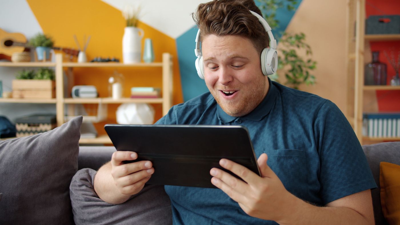 Kulaklıkla tablet kullanan kişi